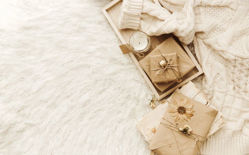 Flat lay cozy composition with wrapped gift box, craft letter and warm sweater