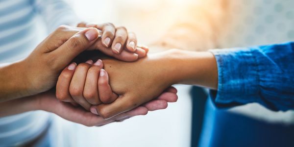 Two people holding hands in a comforting gesture.