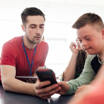 Teacher assisting student with phone use.