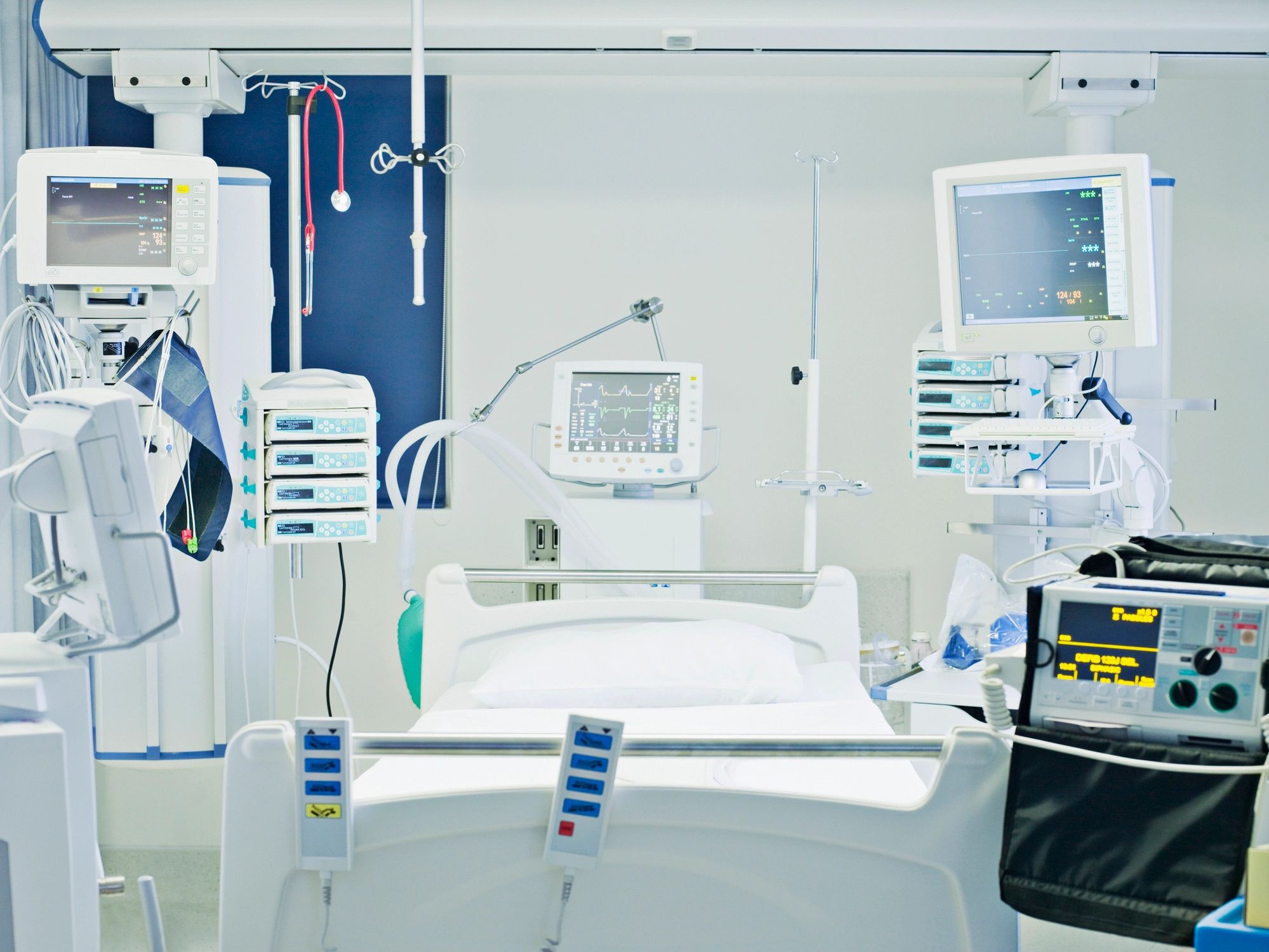Empty intensive care unit with medical monitors and equipment.