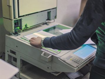 Person using a photocopier machine in an office setting.