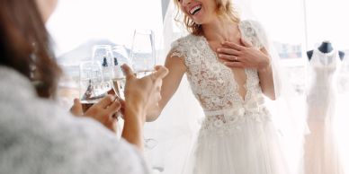 Bride celebrating with friends while trying on a wedding dress.