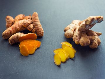 Fresh turmeric and ginger roots with sliced pieces.
