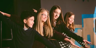 Four kids with arms extended, smiling.