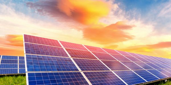 Solar panels under a vibrant sunset sky.