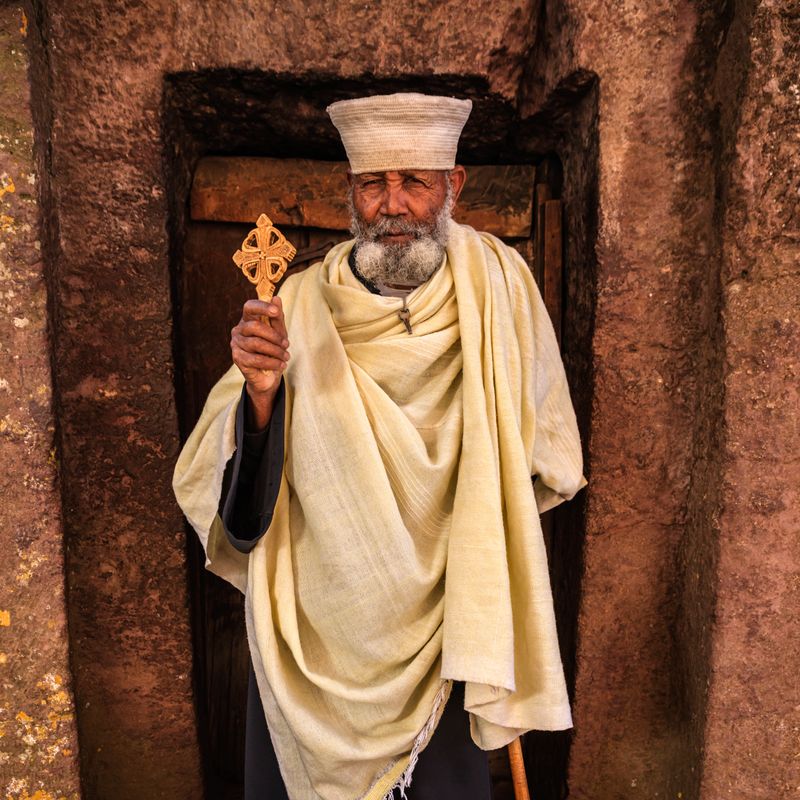 Catholic priest standing in the front of one of rock-hewn churches in Lalibela. Ethiopia,East Africa