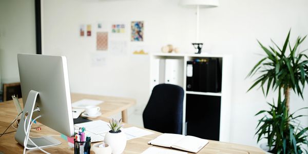 Modern minimalist office desk with computer and plants.
