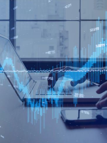 Person analyzing financial data on laptop with digital stock charts overlay.