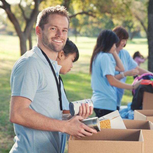 Volunteer packing canned goods into boxes outdoors.