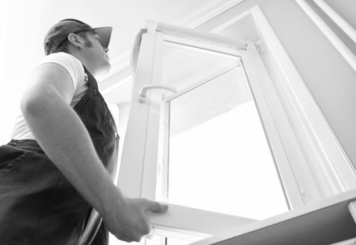 Man in uniform opening a window indoors.