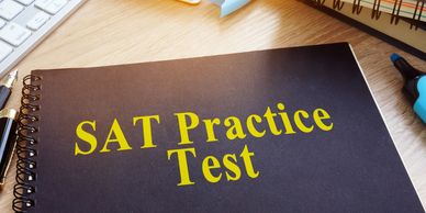 A black spiral notebook titled SAT Practice Test on a wooden desk.