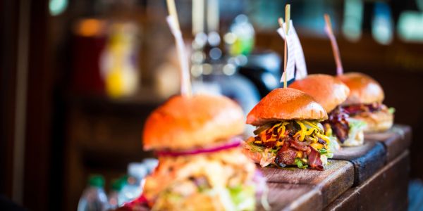 Three gourmet burgers lined up on a wooden counter.