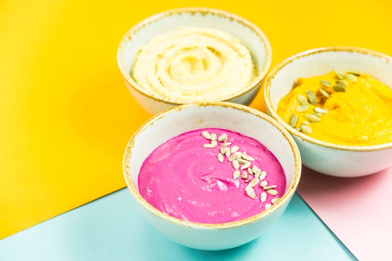 bright appetizers in the form of vegetable sauces and hummus of chickpeas on a combination multicolored background