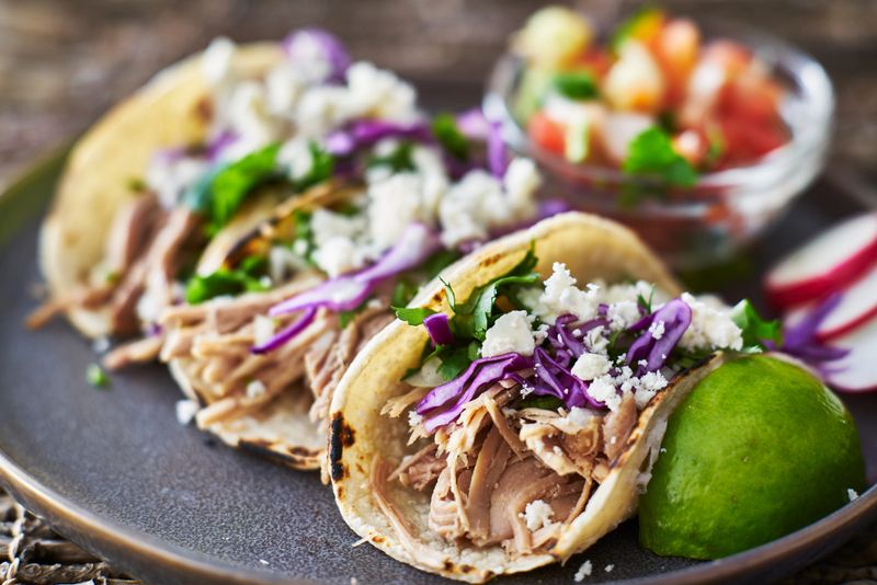 mexican street tacos with seasoned pork carnitas, red cabbage and queso fresco cheese