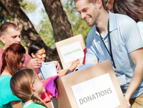 A man holding a donation box with children in front 