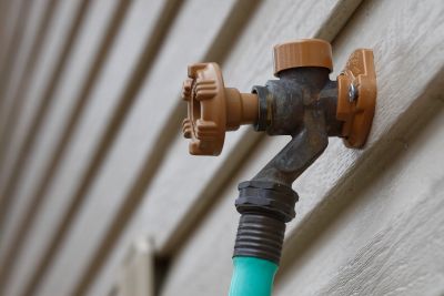 Outdoor water faucet with a hose attached.
