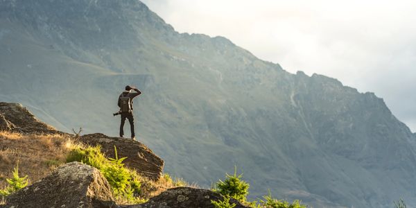 Hiker standing on rock overlooking mountain.
