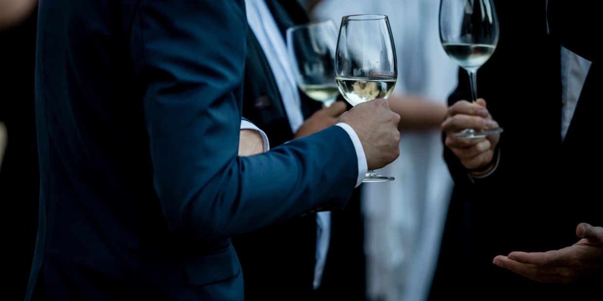 Personas brindando con copas de vino blanco en evento.