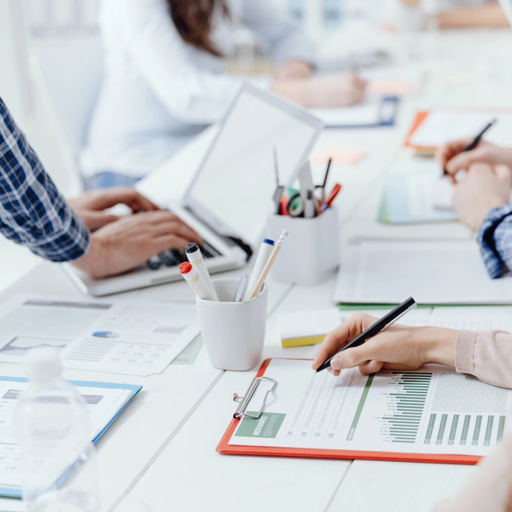 People working on financial documents and laptops in a bright office.