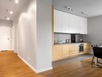 Modern kitchen with wood and white cabinetry in an open living space.