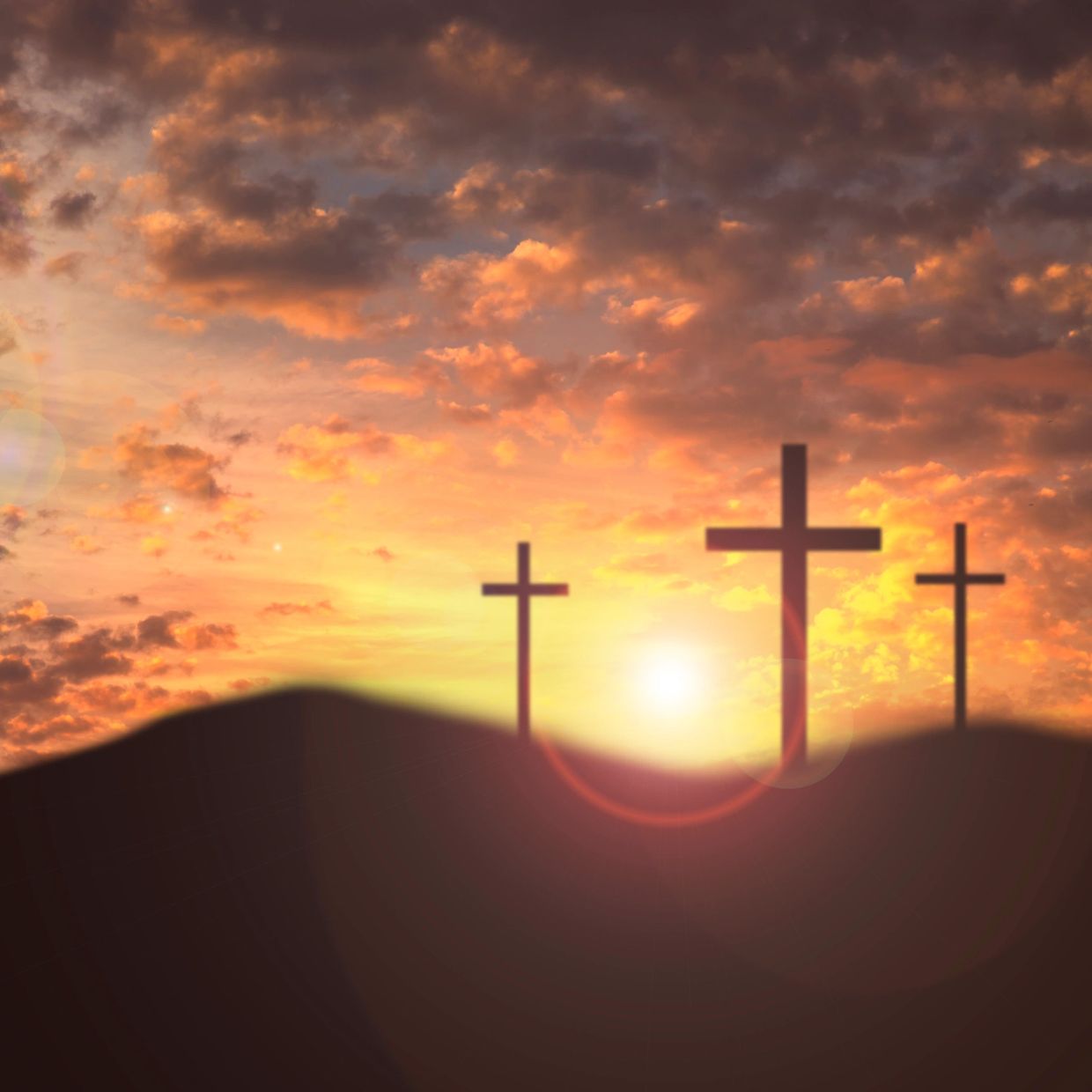 Three crosses silhouetted against a vibrant sunset sky.