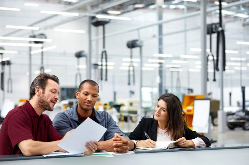 Automobile engineers and supervisor discussing in office. Multi-ethnic male and female colleagues are having meeting at table. They are working at car manufacturing industry.