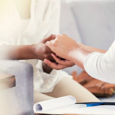 Two people holding hands in a comforting gesture during a conversation.