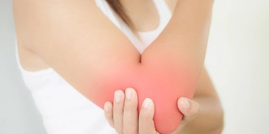 Person holding their painful, reddened elbow in discomfort.