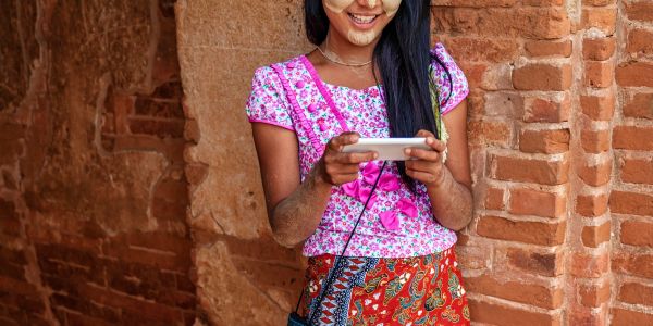 Young woman smiling and playing a game on her phone.