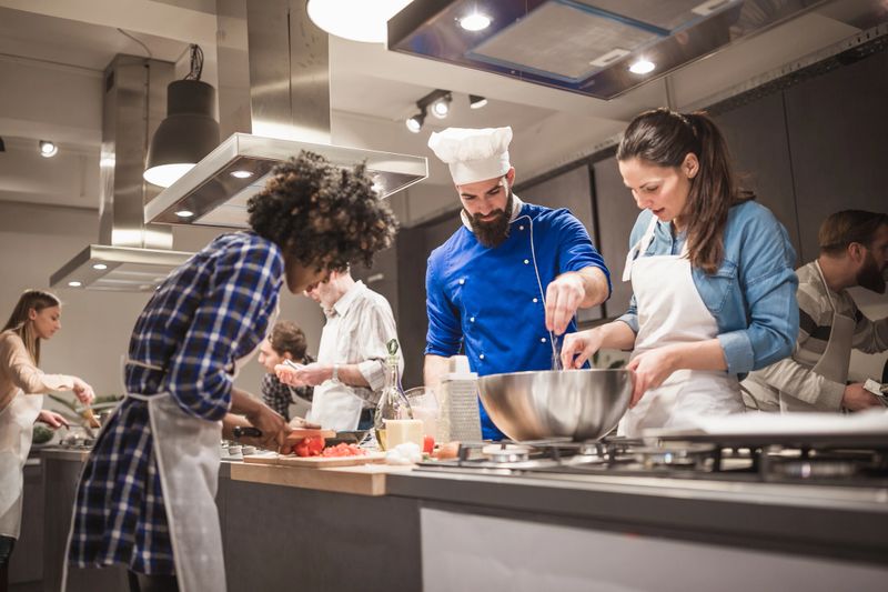 Chef is supervising attendees of cooking class while they are making meals