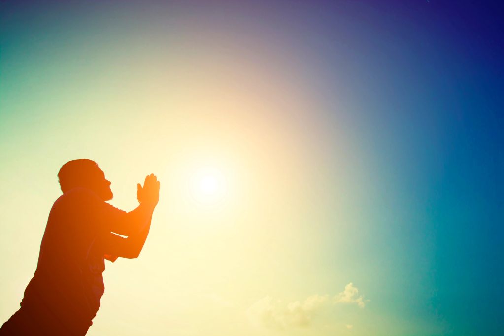 Silhouette of a man praying at sunset.