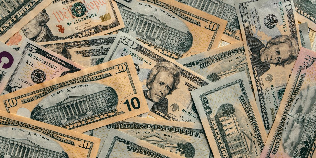 Various denominations of US dollar bills scattered together.