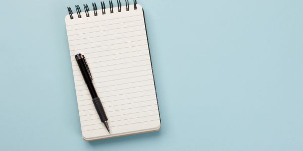 Black pen on a lined notepad with blue background.