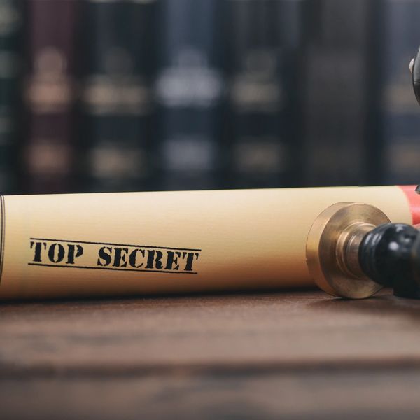 A document tube labeled 'TOP SECRET' placed on a wooden surface.