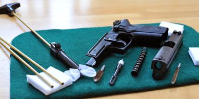 Disassembled handgun with cleaning tools on a green mat.
