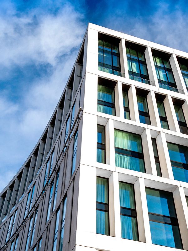 Modern curved building facade with large windows against a blue sky.