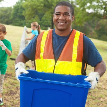 Man in safety vest holding recycling bin.