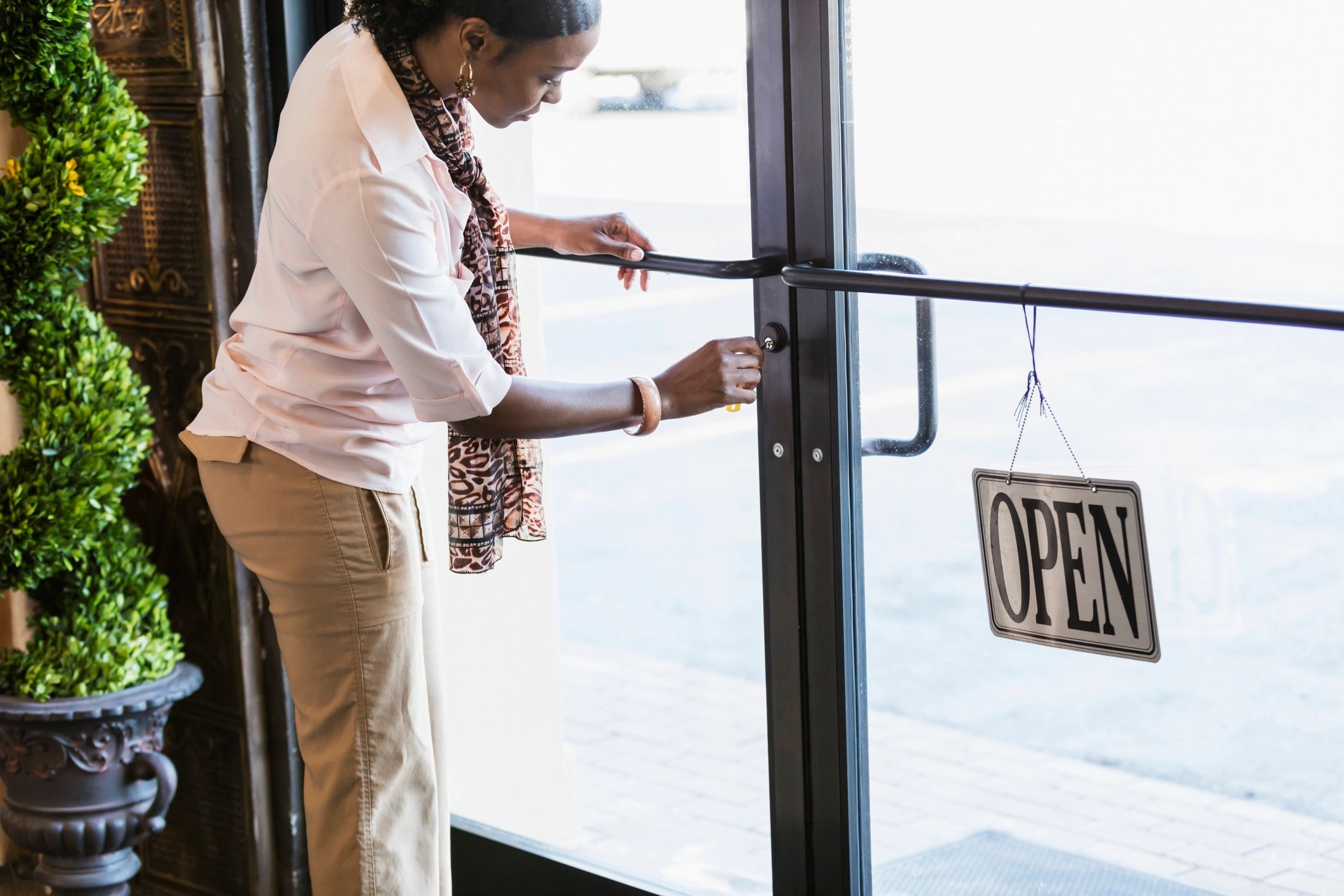 Woman unlocking a glass door with an open sign.