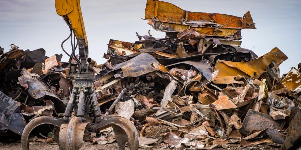 Heavy machinery grabs scrap metal at a junkyard.
