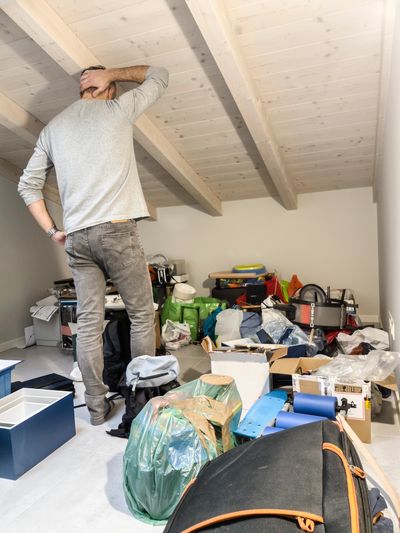 Man contemplating a cluttered attic space.