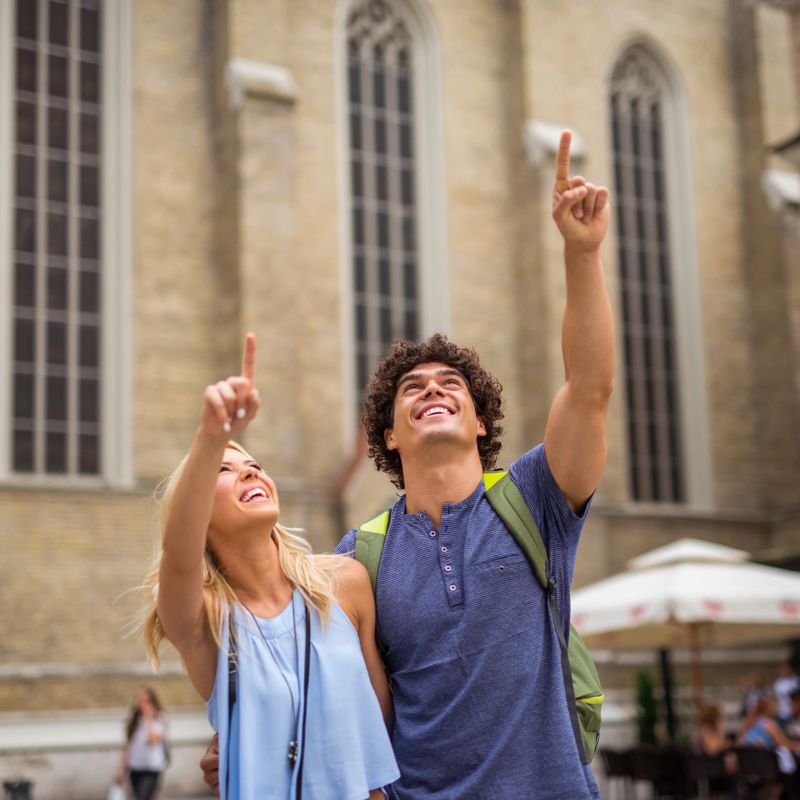 Happy couple pointing with finger while sightseeing in the city.