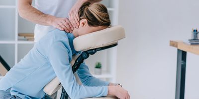 A woman receiving a neck massage while seated on a massage chair.