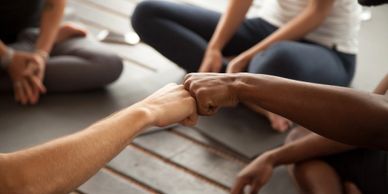 Two people fist bumping while sitting cross-legged on the floor.