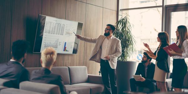 Businessman presenting data charts to colleagues in a meeting room.
