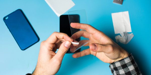 Person applying a screen protector to a smartphone.