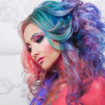 Woman with colorful, vibrant curly hair and artistic makeup.