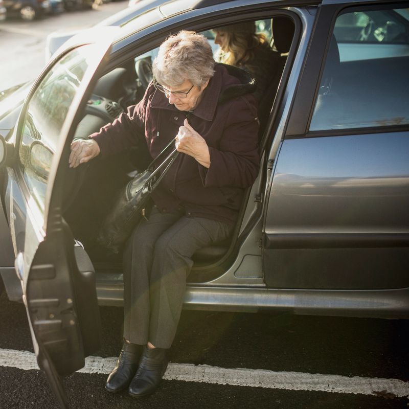 Senior woman getting out of a car.