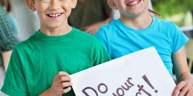 Two smiling boys holding a sign that says 'Do your best!'