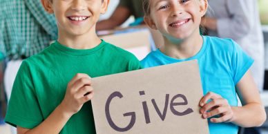 Two kids holding a sign that says "Give".