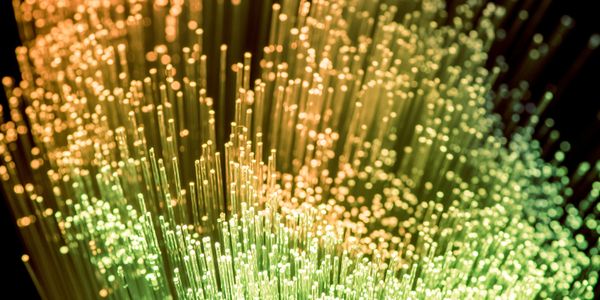 Close-up of colorful fiber optic cables glowing in green and yellow hues.
